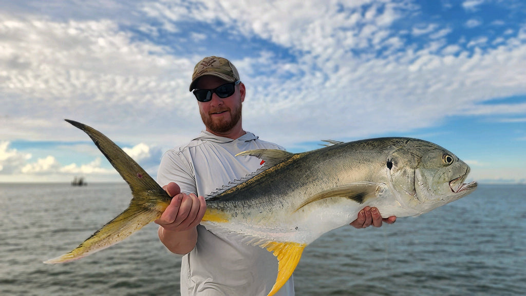 Angler holding a silver fish with yellow fins
